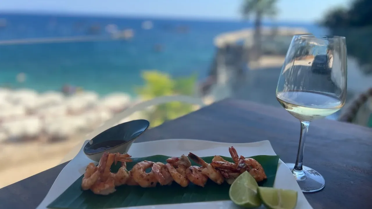 Grilled prawns and white wine at a seafront table in Dhërmi