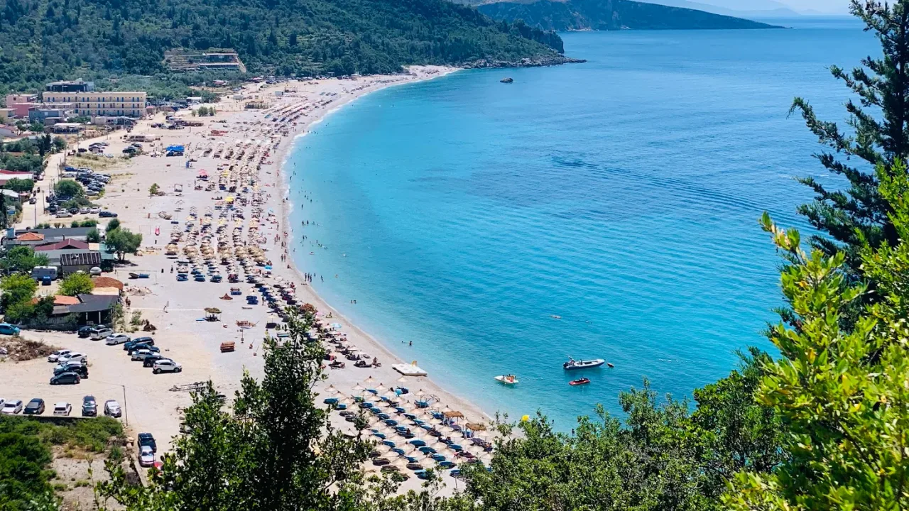 Thatched umbrellas and sunbeds along a long Riviera beach near Himarë