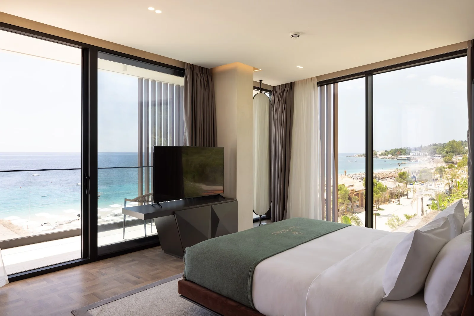 A contemporary beachfront hotel with a pool above the turquoise water at Dhërmi on the Albanian Riviera