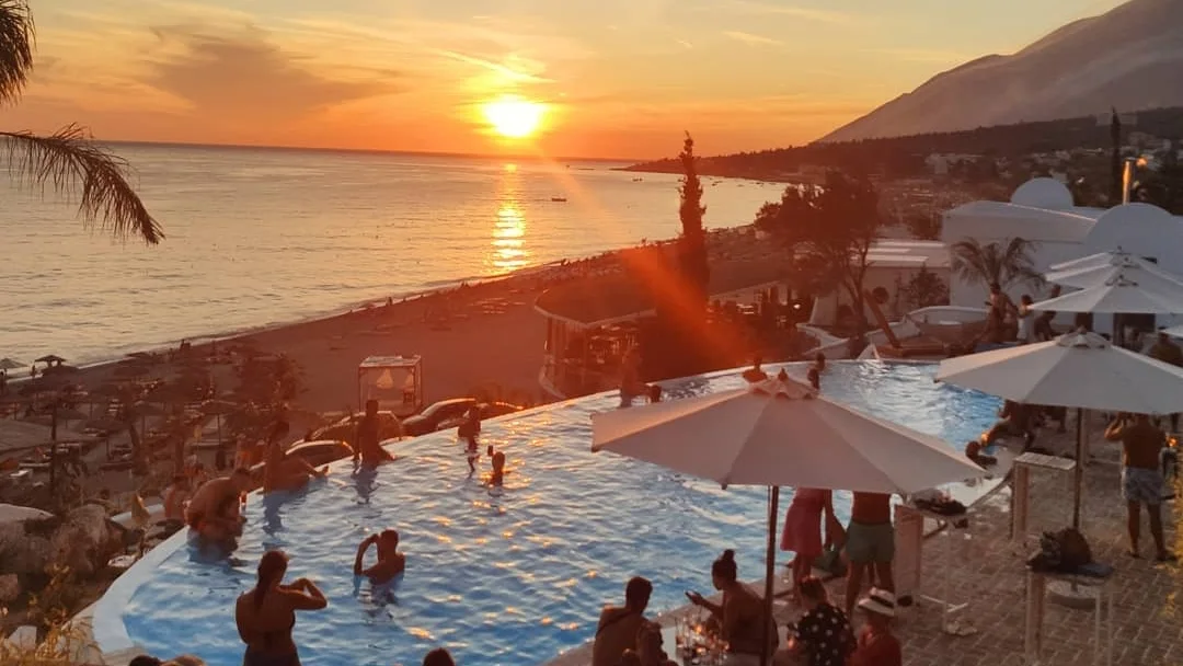 The infinity pool and beach at Havana Beach Club at sunset on the Dhërmi shore