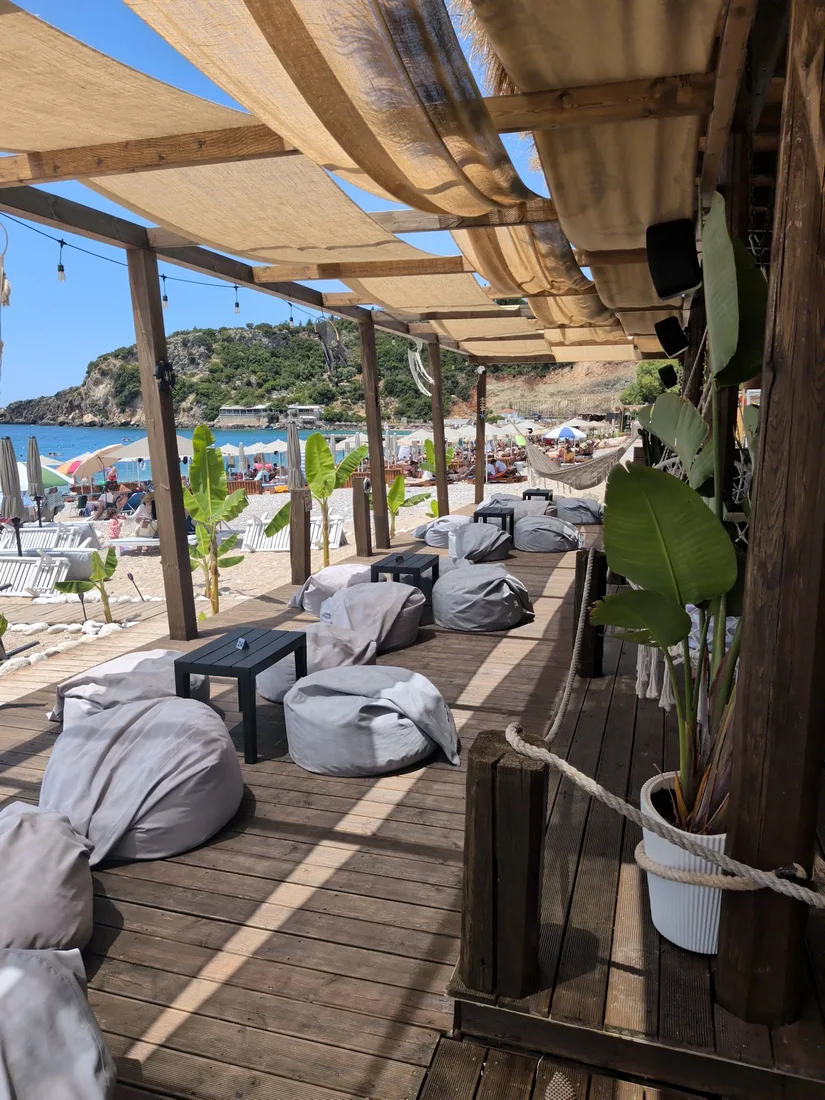 Grey beanbags on a thatched wooden deck looking over the beach cove at Paralian Beach Bar, Livadhi