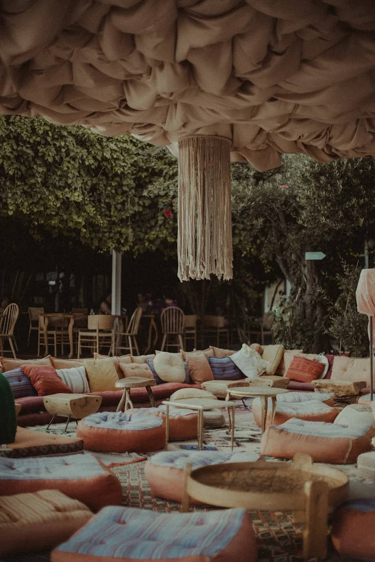 The draped-fabric ceiling and floor-cushion lounge under a macramé chandelier at 360° Sunset Bar, Drymades