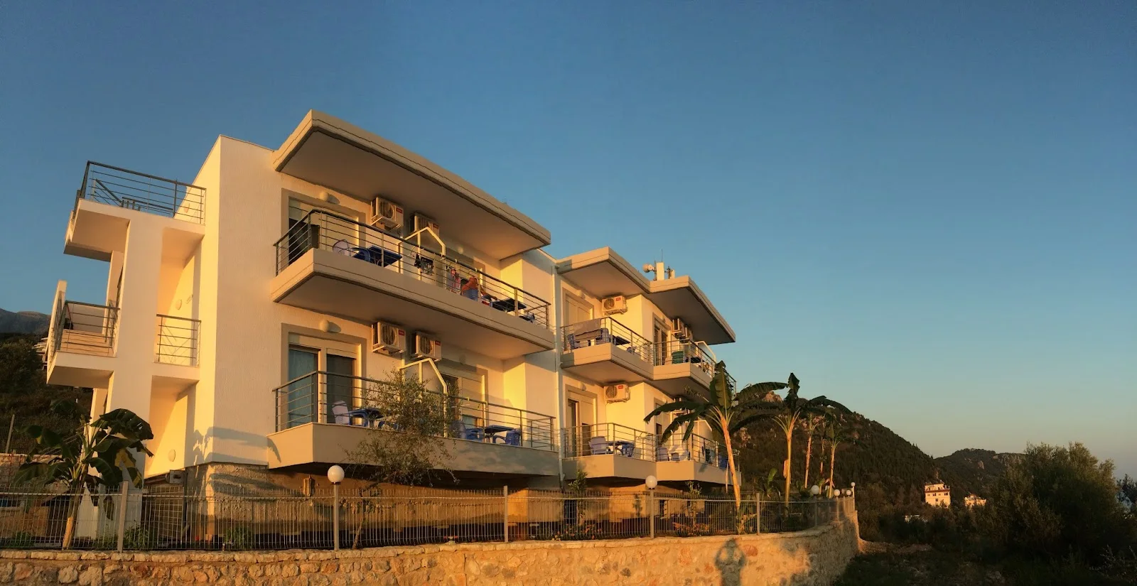 The white balconied facade of Sea View Hotel above Dhërmi beach at golden hour