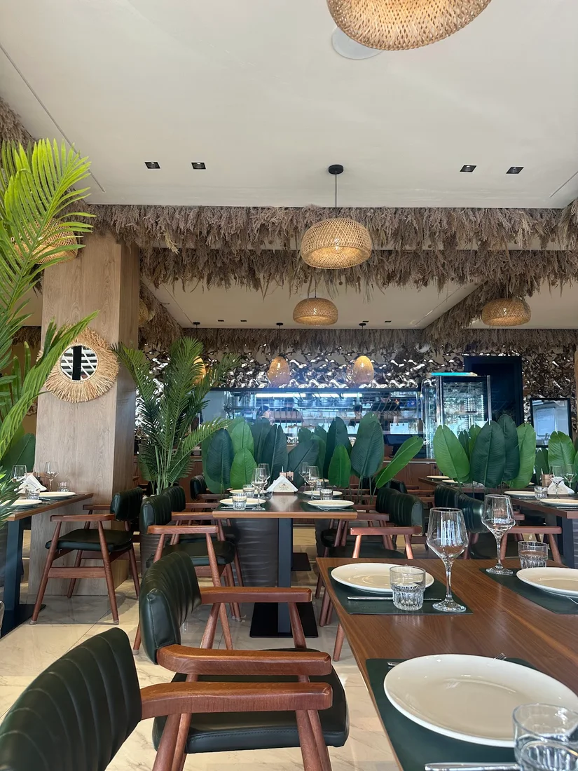 The plant-filled dining room under pampas-grass ceilings at Soleil Restorant on Dhërmi Beach