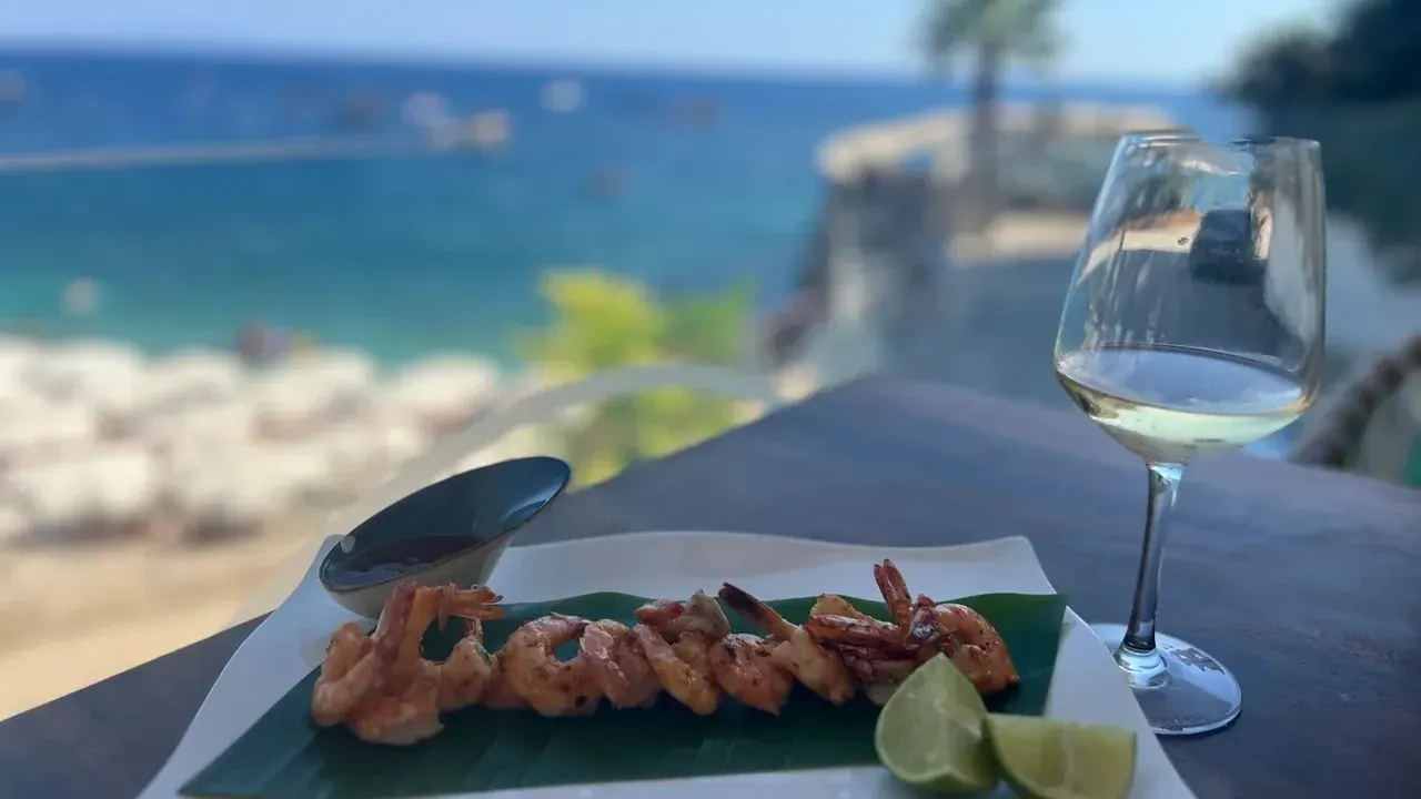 Grilled prawns and white wine at a seafront table in Dhërmi