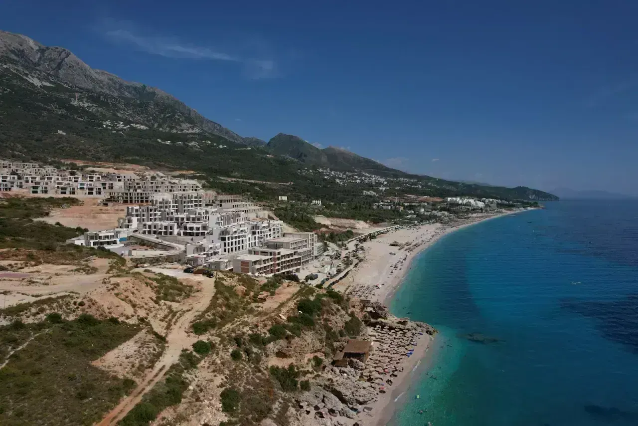 The village, beaches and turquoise water of Dhërmi below the Ceraunian Mountains from above