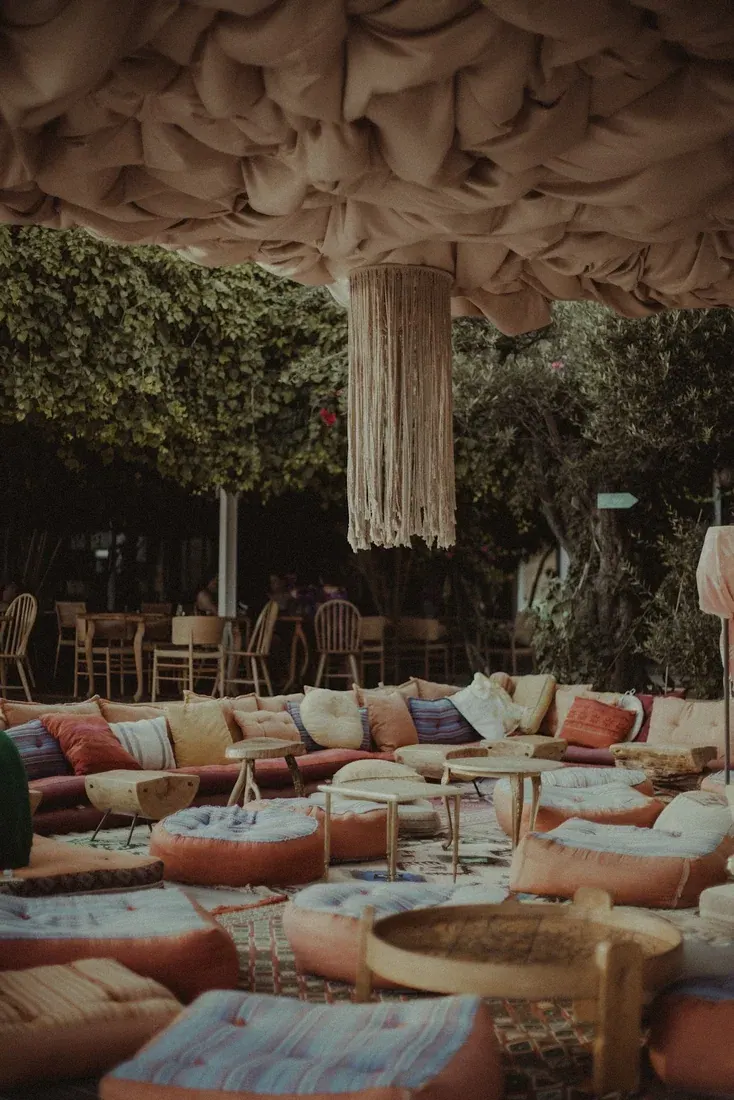 The draped-fabric ceiling and floor-cushion lounge under a macramé chandelier at 360° Sunset Bar, Drymades