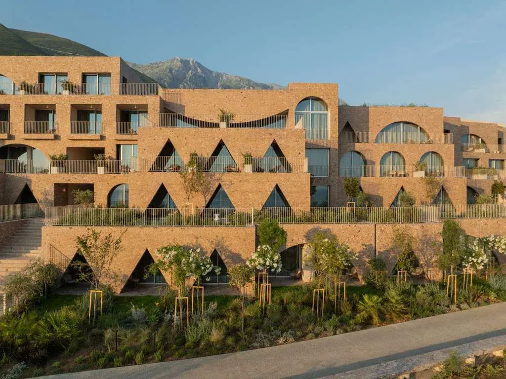 The arched stone facade of Green Coast Hotel MGallery below the mountains at Palasë