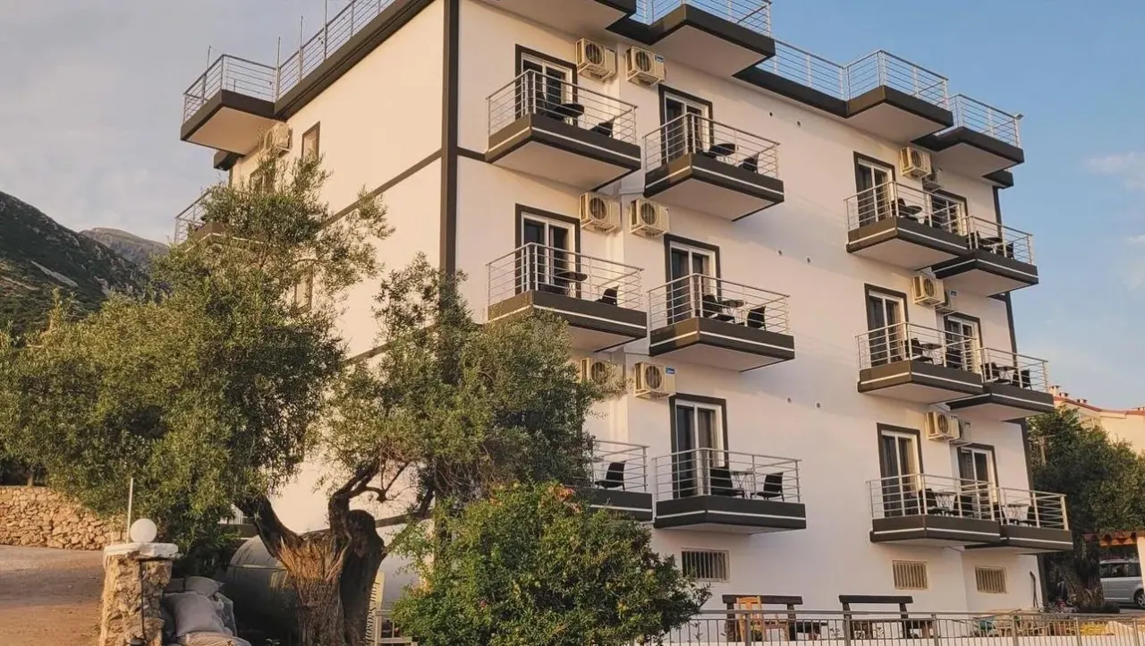 The white balconied facade of Season Inn against the mountains at Palasë