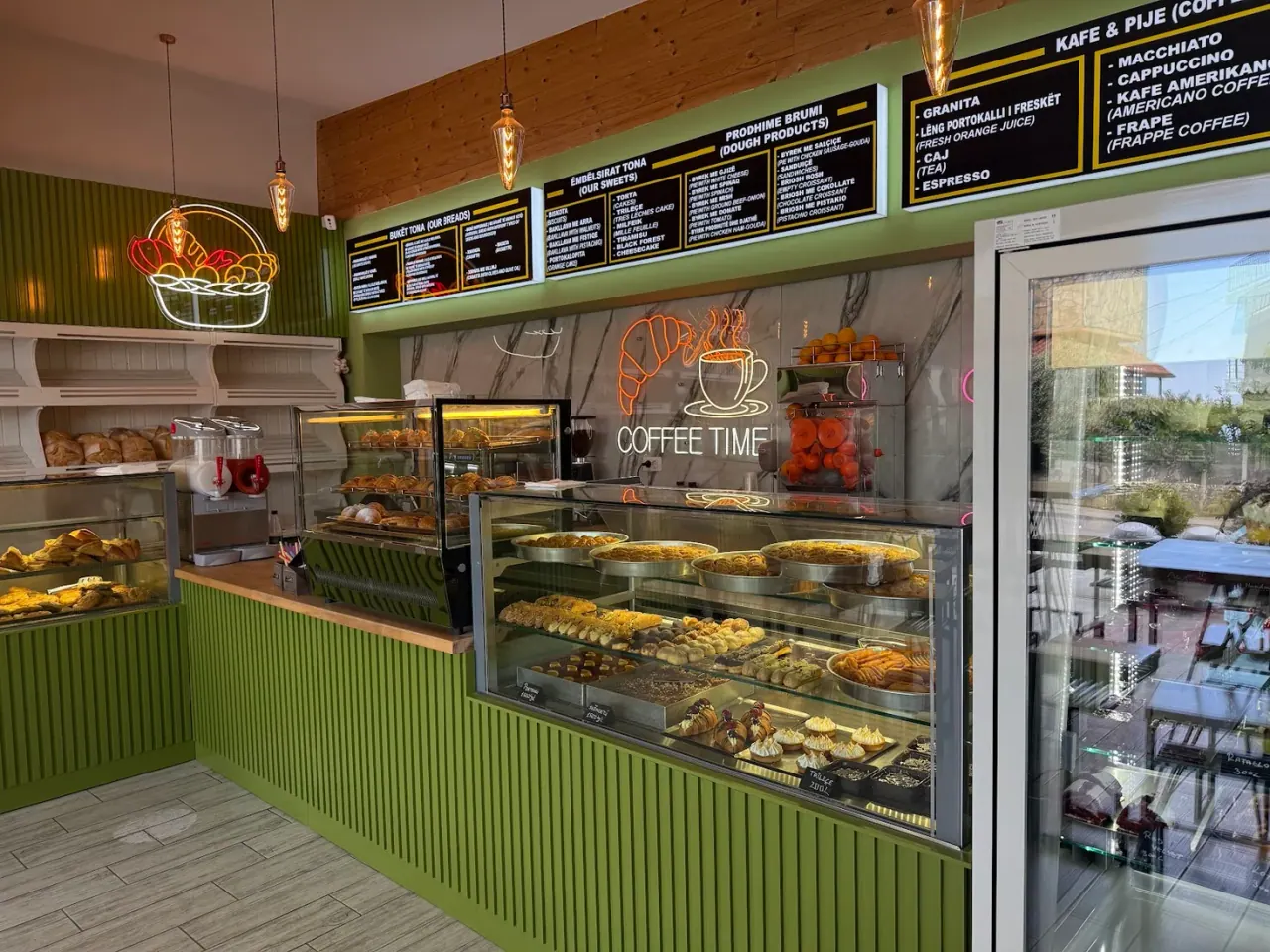 The pastry counter and Albanian-and-English menu boards inside Barba Niko Bakery in Dhërmi