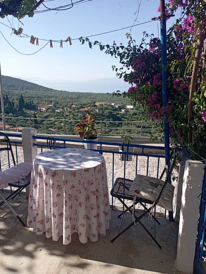 A bougainvillea-shaded terrace table at Mom's Food in Vuno village looking over olive groves to the sea
