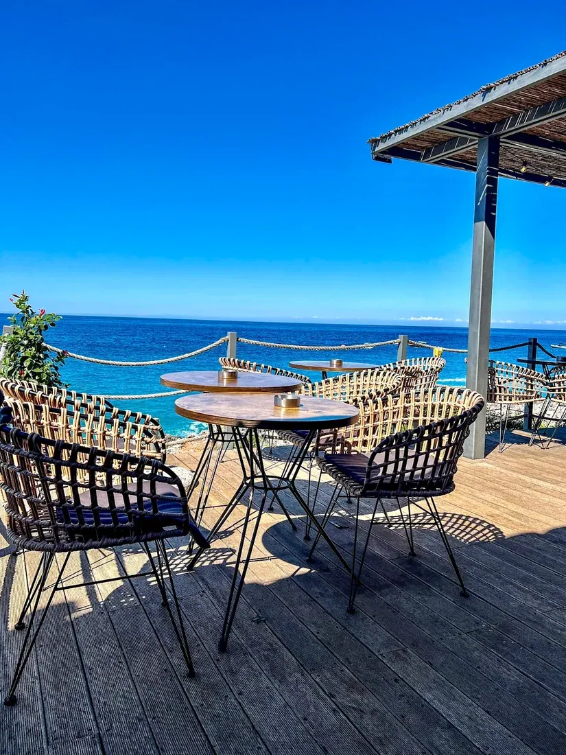 The rope-railed deck of Morsi Drymades set with tables above the turquoise Ionian at Drymades