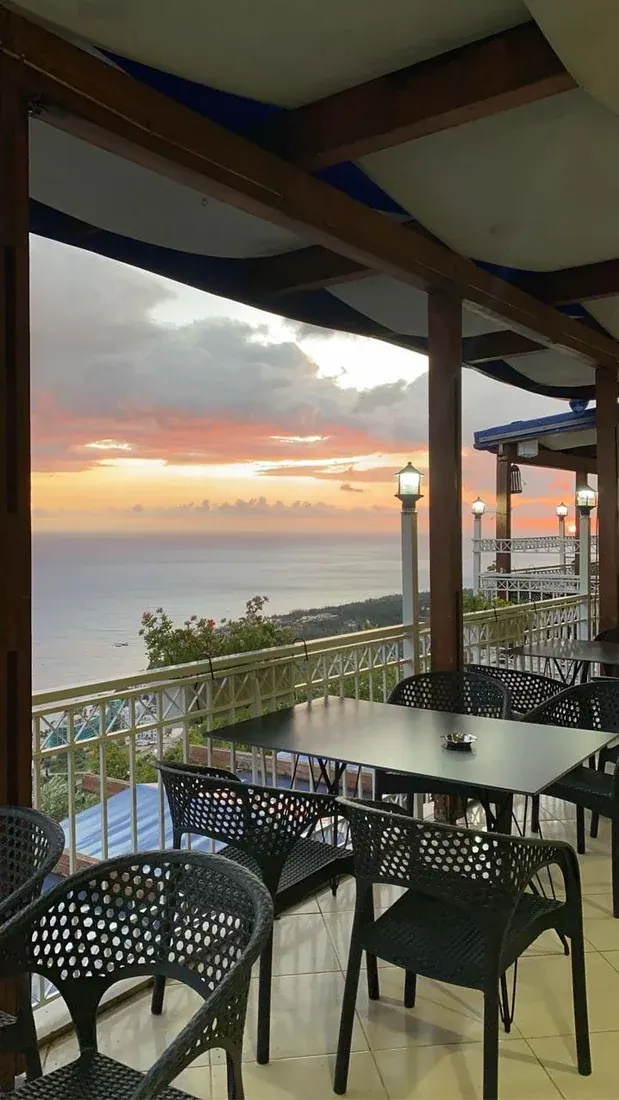 A covered hillside terrace looking out over the coast at sunset at Panorama Dhërmi