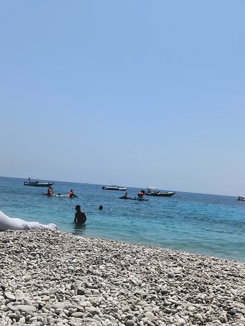 Strand van Dhërmi — turquoise Ionisch water en een witte kiezelkust onder de Ceraunische Bergen