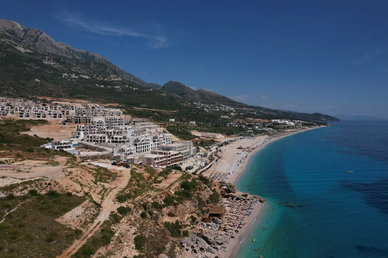 The pine-backed shore and clear water of Drymades on an Albanian Riviera boat tour